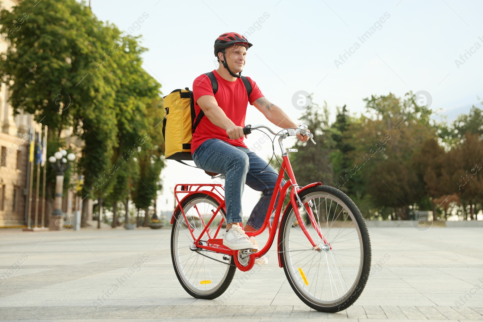 Courier with thermo bag riding bicycle outdoors. Food delivery service Photo of Courier with thermo bag riding bicycle outdoors. Food delivery service