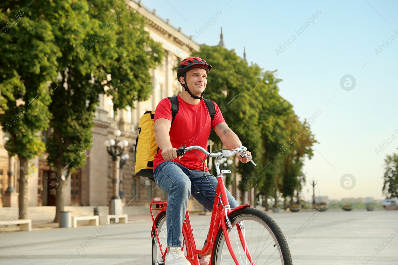 Courier with thermo bag riding bicycle outdoors. Food delivery service Photo of Courier with thermo bag riding bicycle outdoors. Food delivery service