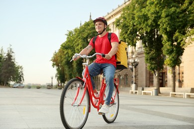 Photo of Courier with thermo bag riding bicycle outdoors. Food delivery service