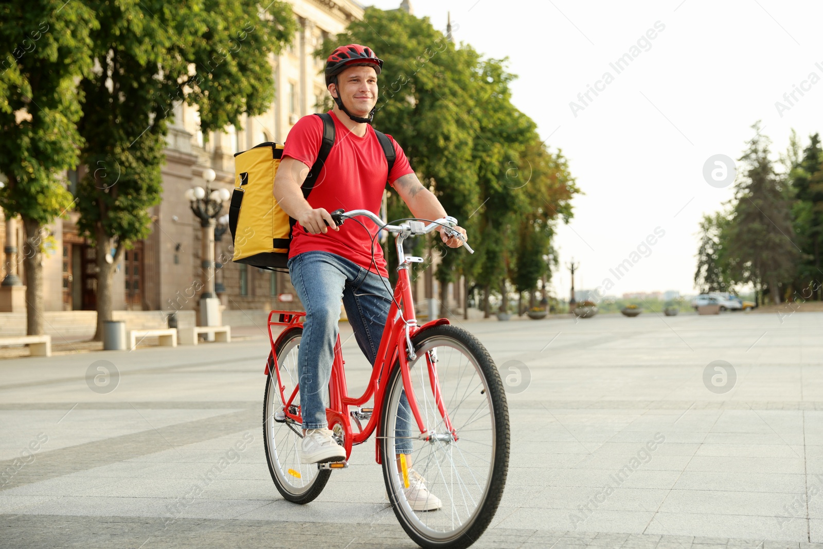 Courier with thermo bag riding bicycle outdoors. Food delivery service Photo of Courier with thermo bag riding bicycle outdoors. Food delivery service