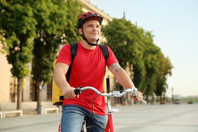 Photo of Courier with thermo bag on bicycle outdoors. Food delivery service