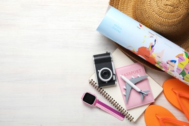 Photo of Time for summer vacation. Passport, toy plane, notebook, smart watch, camera, world map and beach accessories on light wooden table, flat lay. Space for text