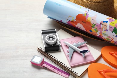 Photo of Time for summer vacation. Passport, toy plane, notebook, smart watch, camera, world map and beach accessories on light wooden table, closeup. Space for text