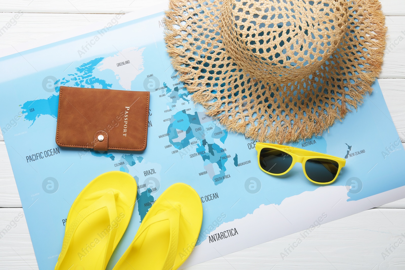 Photo of Time for summer vacation. Passport, world map and beach accessories on white wooden table, flat lay