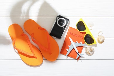Photo of Time for summer vacation. Toy plane, passport, camera and beach accessories on white wooden table, flat lay