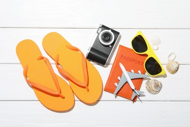 Photo of Time for summer vacation. Toy plane, passport, camera and beach accessories on white wooden table, flat lay