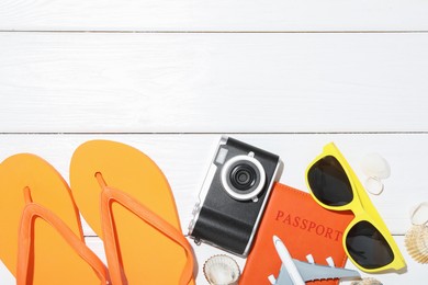 Photo of Time for summer vacation. Toy plane, passport, camera and beach accessories on white wooden table, flat lay. Space for text