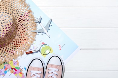 Photo of Time for summer vacation. Toy plane, magnifying glass, shoes, straw hat and world map on white wooden table, flat lay. Space for text