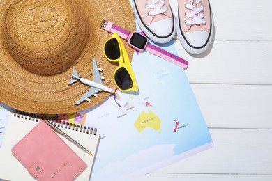 Photo of Time for summer vacation. Passport, stationery, toy plane, smart watch, shoes, beach accessories and world map on white wooden table, flat lay. Space for text