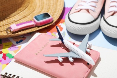 Photo of Time for summer vacation. Passport, notebook, toy plane, smart watch, shoes, straw hat and world map on table, closeup