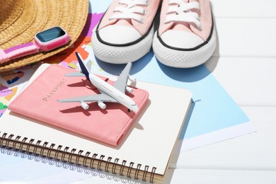 Photo of Time for summer vacation. Passport, notebook, toy plane, smart watch, straw hat, shoes and world map on white wooden table, closeup