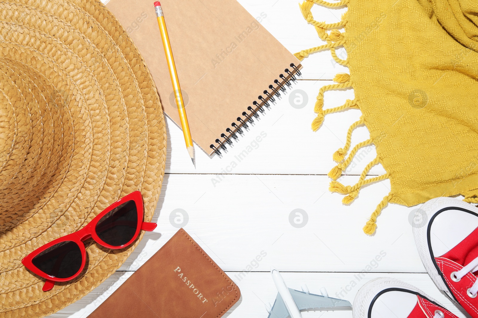Photo of Time for summer vacation. Passport, stationery, toy plane, shoes and beach accessories on white wooden table, flat lay. Space for text
