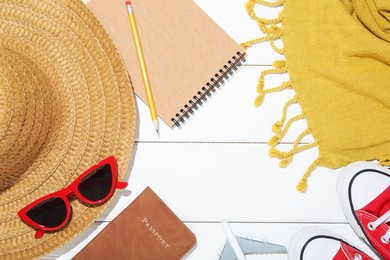 Photo of Time for summer vacation. Passport, stationery, toy plane, shoes and beach accessories on white wooden table, flat lay. Space for text