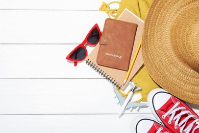 Photo of Time for summer vacation. Passport, stationery, toy plane, shoes and beach accessories on white wooden table, flat lay. Space for text