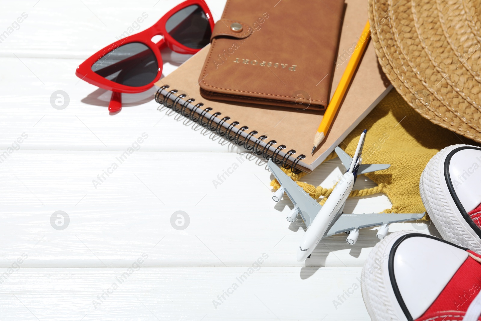 Photo of Time for summer vacation. Passport, stationery, toy plane, shoes and beach accessories on white wooden table, closeup. Space for text