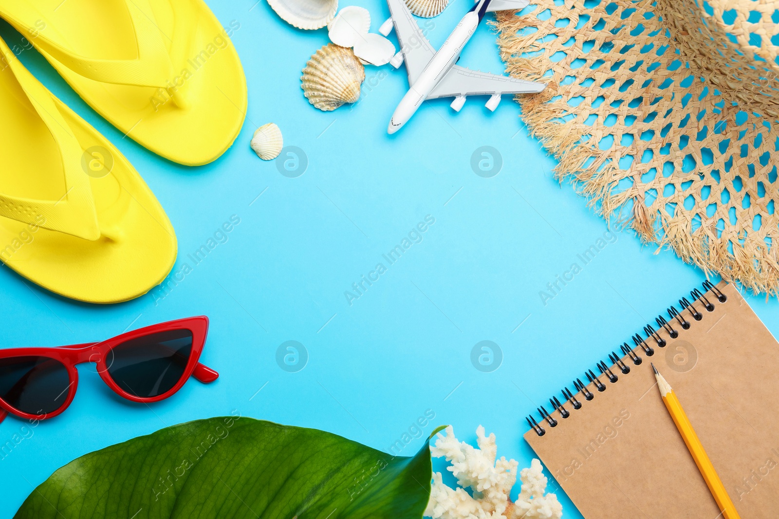 Photo of Time for summer vacation. Notebook, toy plane, green leaf and beach accessories on light blue background, flat lay. Space for text