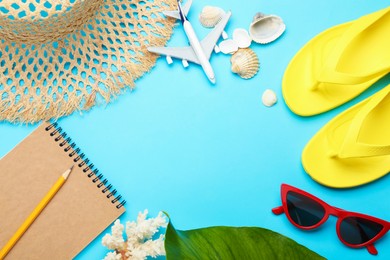 Photo of Time for summer vacation. Notebook, toy plane, green leaf and beach accessories on light blue background, flat lay. Space for text