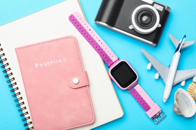 Photo of Time for summer vacation. Passport, notebook, toy plane, camera, smart watch and seashells on light blue background, flat lay