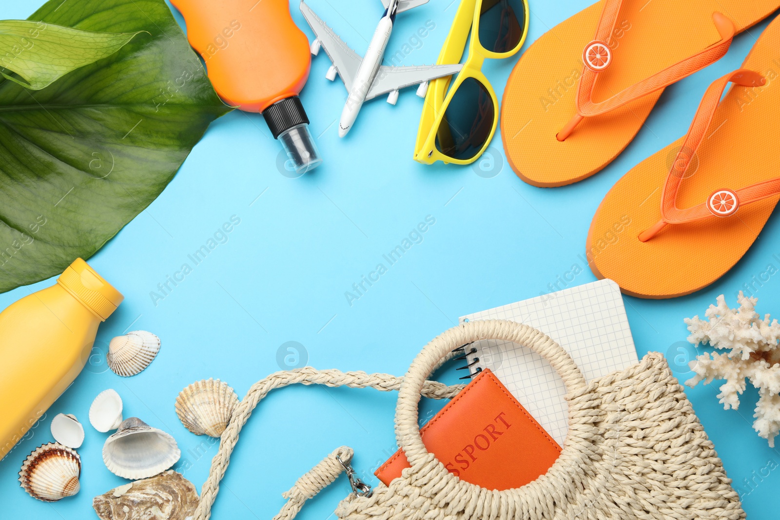 Photo of Time for summer vacation. Passport, notebook, toy plane, green leaf and beach accessories on light blue background, flat lay. Space for text