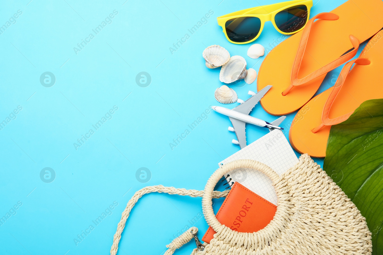 Photo of Time for summer vacation. Passport, notebook, toy plane, green leaf and beach accessories on light blue background, flat lay. Space for text