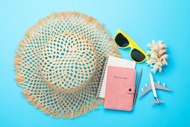Photo of Time for summer vacation. Passport, notebook, pen, toy plane and beach accessories on light blue background, flat lay