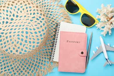 Photo of Time for summer vacation. Passport, notebook, pen, toy plane and beach accessories on light blue background, flat lay