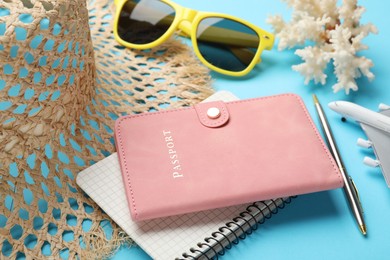 Photo of Time for summer vacation. Passport, notebook, pen, toy plane and beach accessories on light blue background, closeup