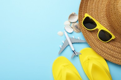 Photo of Time for summer vacation. Toy plane and beach accessories on light blue background, flat lay. Space for text