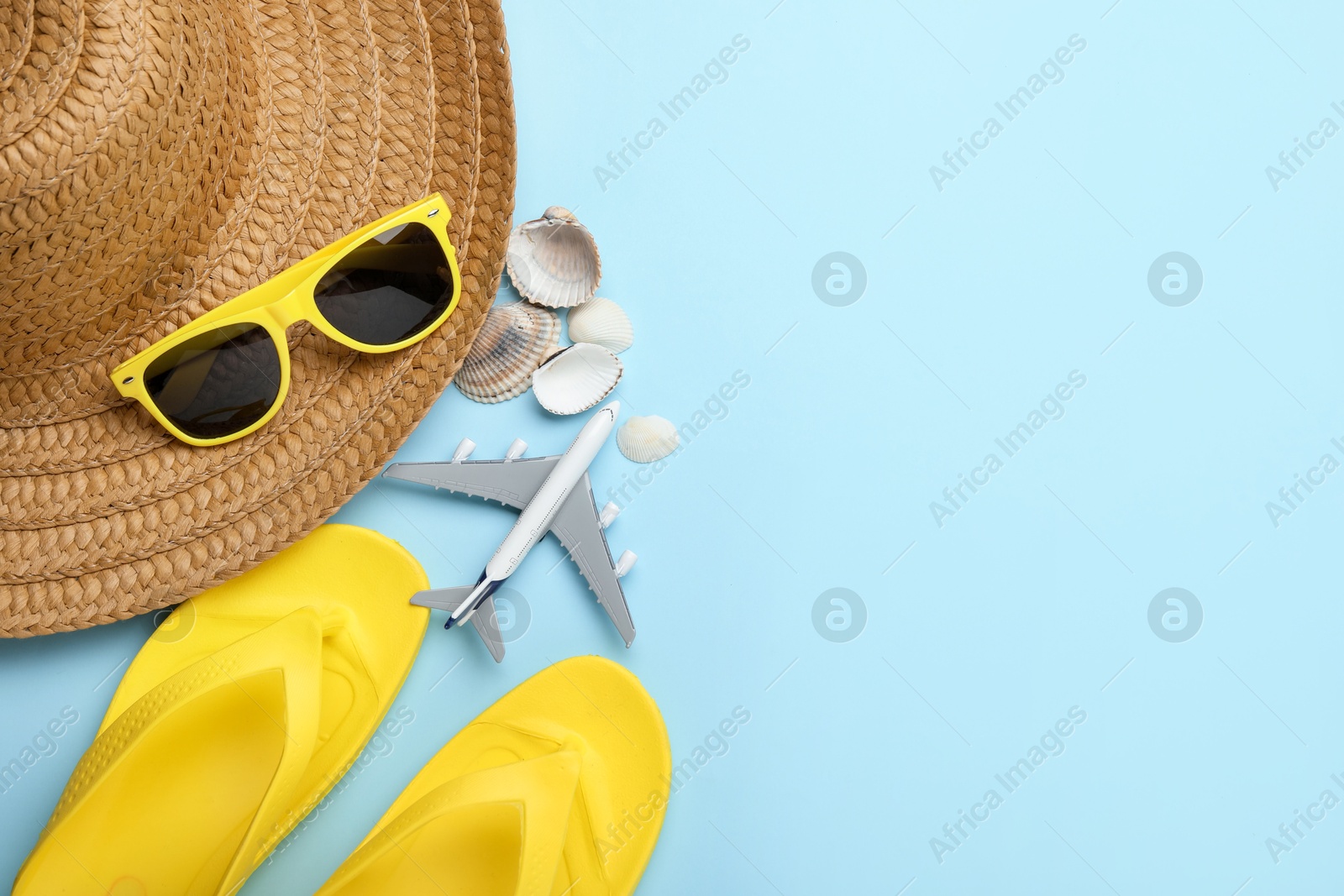 Photo of Time for summer vacation. Toy plane and beach accessories on light blue background, flat lay. Space for text