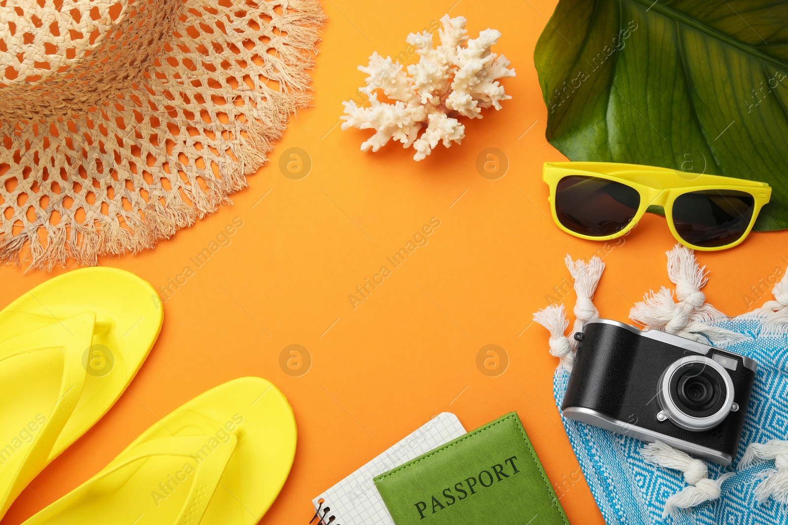 Photo of Time for summer vacation. Passport, notebook, camera, green leaf and beach accessories on orange background, flat lay. Space for text