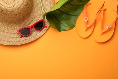 Photo of Time for summer vacation. Beach accessories and green leaf on orange background, flat lay. Space for text
