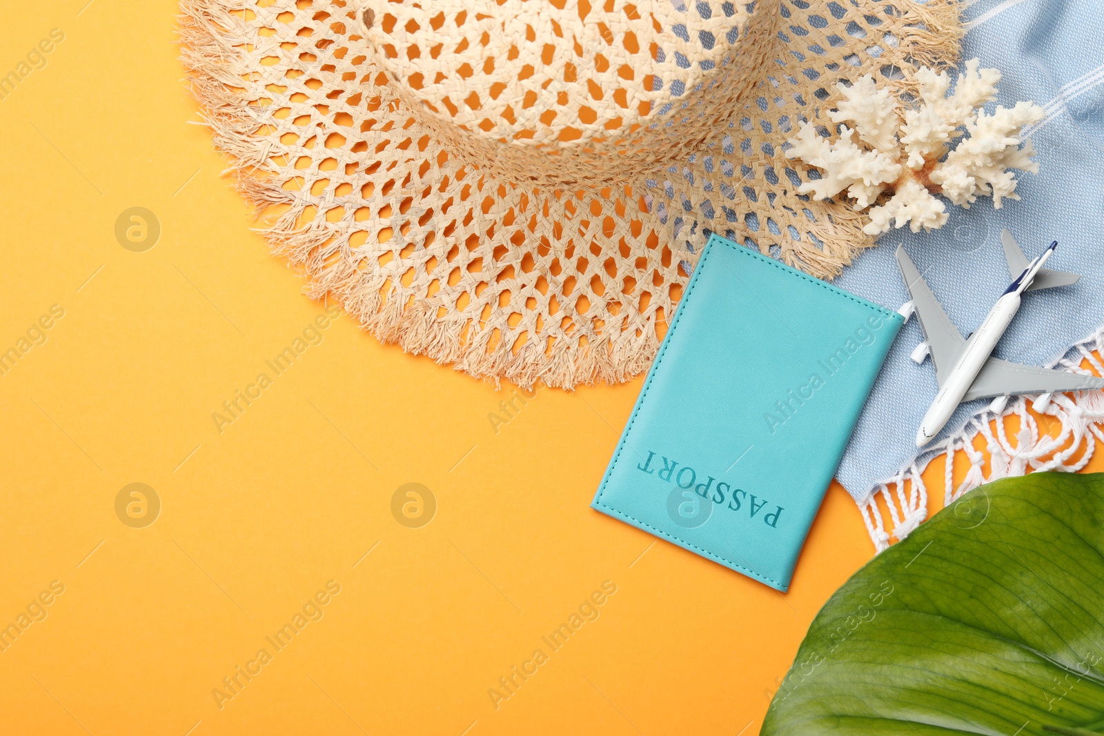Photo of Time for summer vacation. Passport, toy plane, green leaf and beach accessories on orange background, flat lay. Space for text