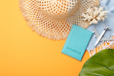 Photo of Time for summer vacation. Passport, toy plane, green leaf and beach accessories on orange background, flat lay. Space for text