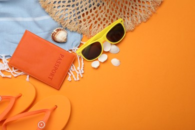 Photo of Time for summer vacation. Passport and beach accessories on orange background, flat lay. Space for text
