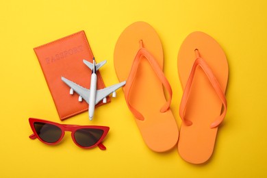 Photo of Time for summer vacation. Passport, toy plane and beach accessories on yellow background, flat lay