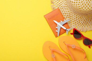 Photo of Time for summer vacation. Passport, toy plane and beach accessories on yellow background, flat lay. Space for text