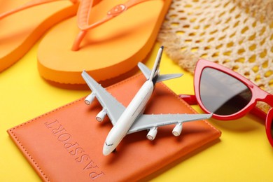Photo of Time for summer vacation. Passport, toy plane and beach accessories on yellow background, closeup