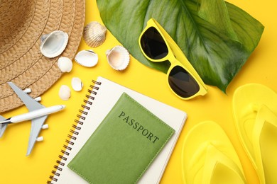Photo of Time for summer vacation. Passport, notebook, toy plane, green leaf and beach accessories on yellow background, flat lay