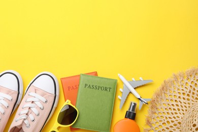 Photo of Time for summer vacation. Toy plane, passports, shoes and beach accessories on yellow background, flat lay. Space for text