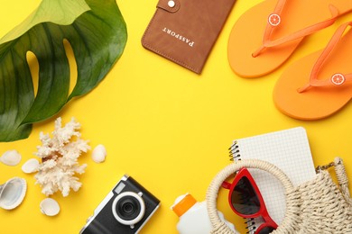 Photo of Time for summer vacation. Passport, notebook, camera, beach accessories and green leaf on yellow background, flat lay. Space for text