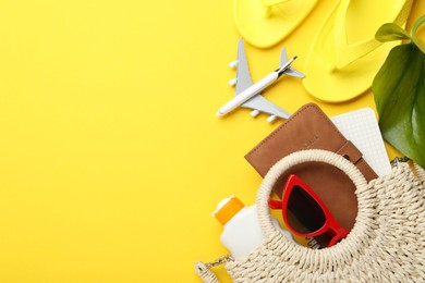 Photo of Time for summer vacation. Passport, notebook, toy plane, beach accessories and green leaf on yellow background, flat lay. Space for text