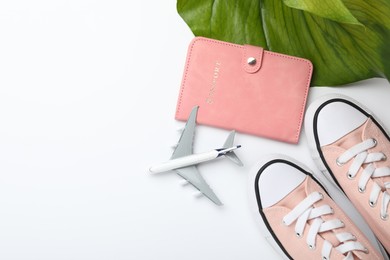 Photo of Time for summer vacation. Passport, toy plane, shoes and green leaf on white background, flat lay. Space for text