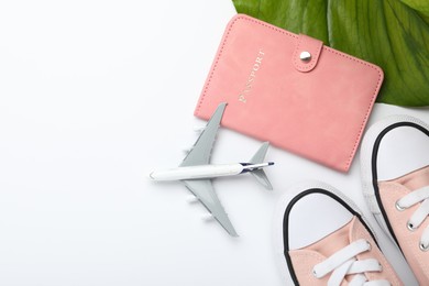 Photo of Time for summer vacation. Passport, toy plane, shoes and green leaf on white background, flat lay. Space for text