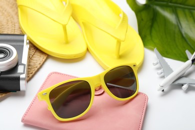 Photo of Time for summer vacation. Beach accessories, passport, toy plane, camera and green leaf on white background, closeup