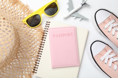Photo of Time for summer vacation. Toy plane, passport, notebook, shoes and beach accessories on white background, flat lay