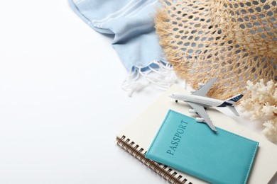 Photo of Time for summer vacation. Toy plane, passport, notebook and beach accessories on white background, closeup. Space for text
