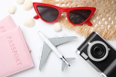 Photo of Time for summer vacation. Toy plane, passports, camera and beach accessories on white background, flat lay