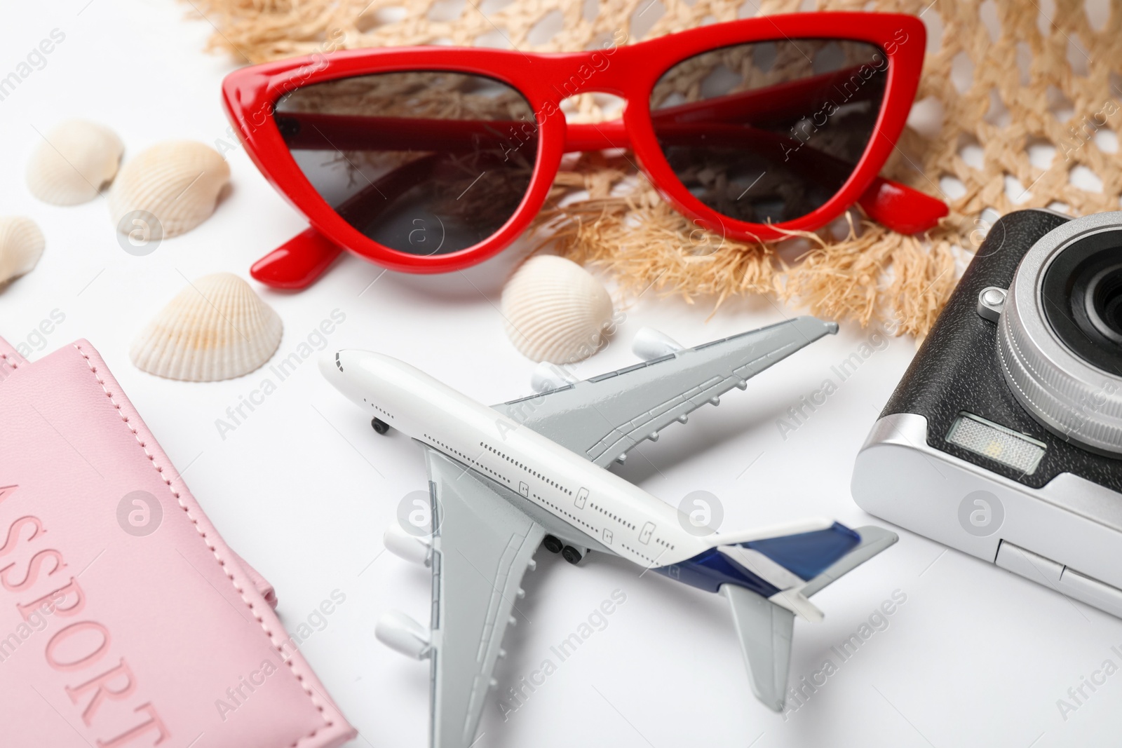 Time for summer vacation. Toy plane, passport, camera and beach accessories on white background, closeup Photo of Time for summer vacation. Toy plane, passport, camera and beach accessories on white background, closeup