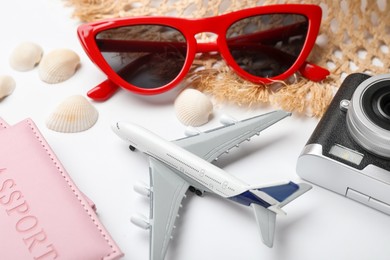 Photo of Time for summer vacation. Toy plane, passport, camera and beach accessories on white background, closeup