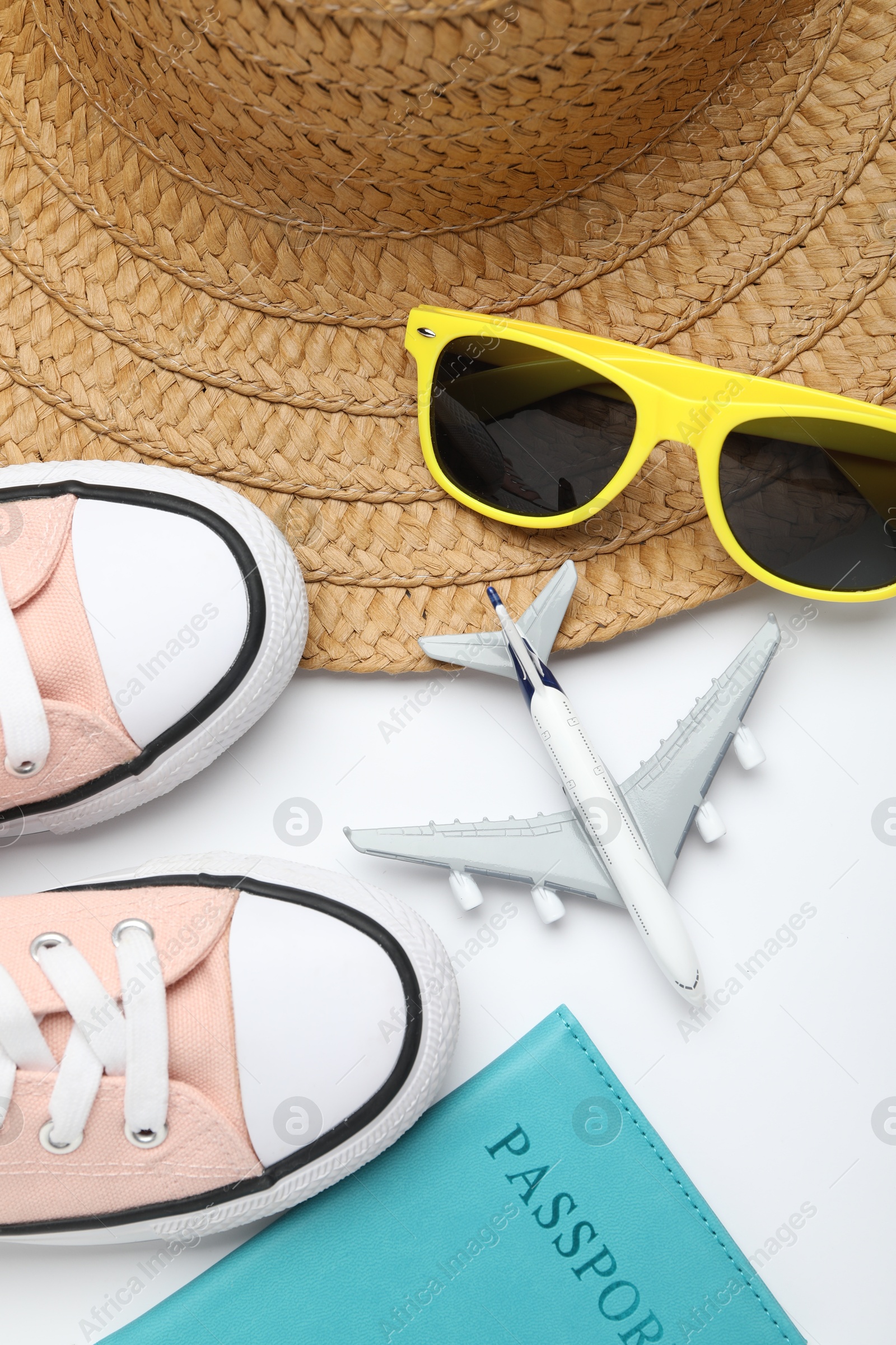 Photo of Time for summer vacation. Toy plane, passport, shoes and beach accessories on white background, flat lay